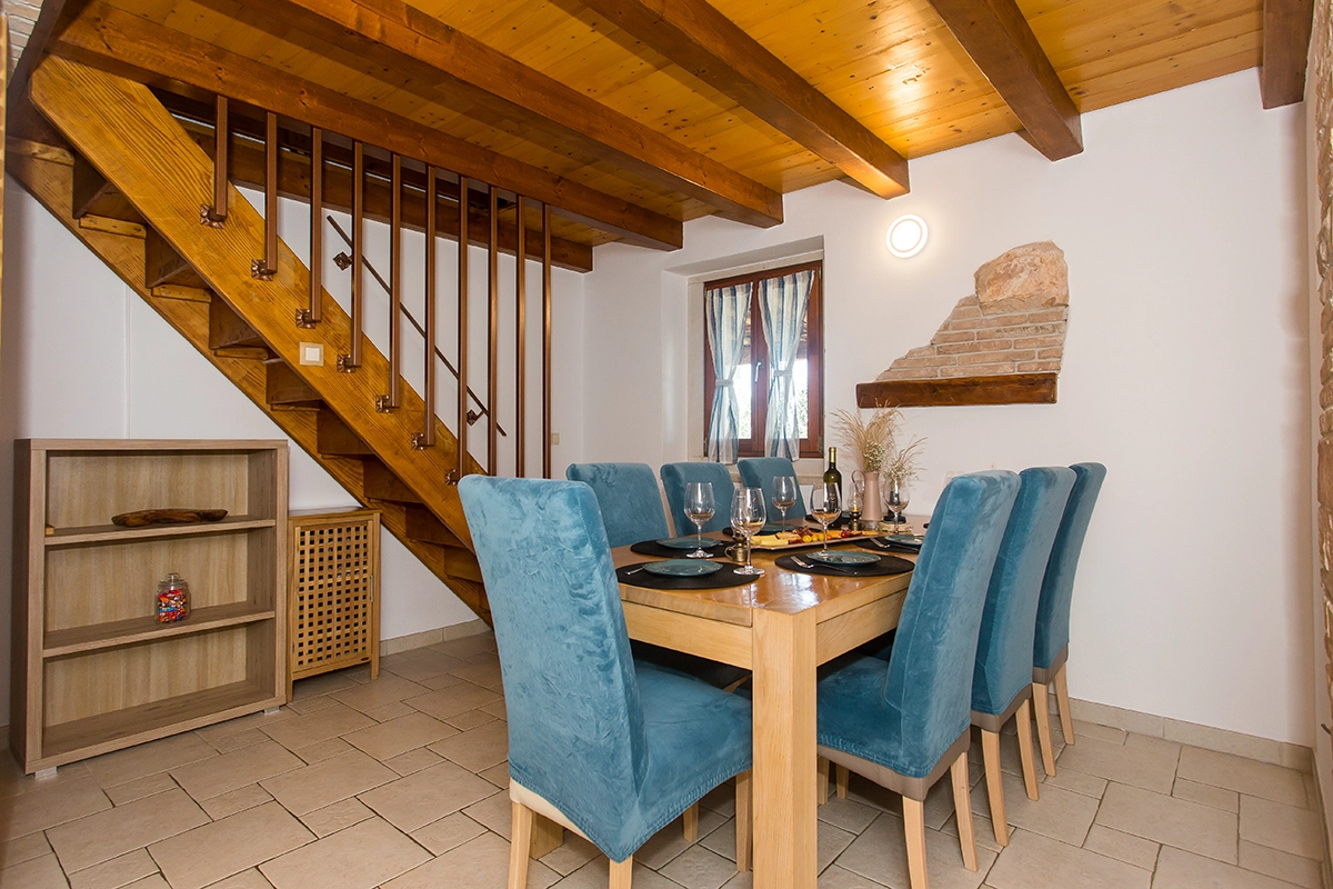 Dining table for eight, with blue chairs and a wooden table, set in an interior of wood and stone.